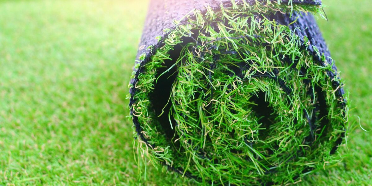 Alfombra de césped artificial que se encuentra enrollado en un jardín