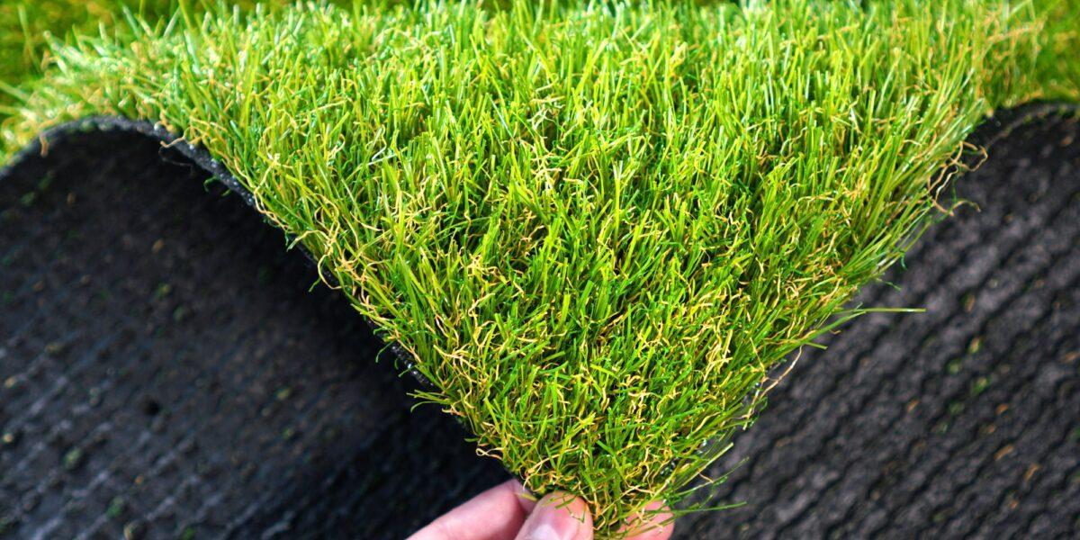 Mano agarrando un trozo de cesped artificial