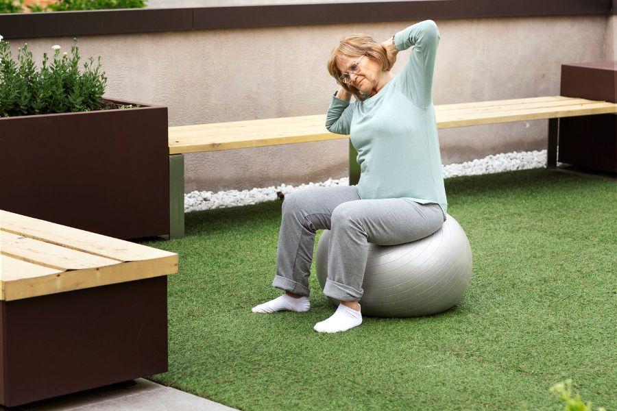 mujer haciendo estiramientos en su terraza con césped artificial